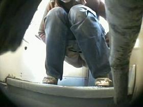 A fresh girl wearing jeans is pissing in the bathroom