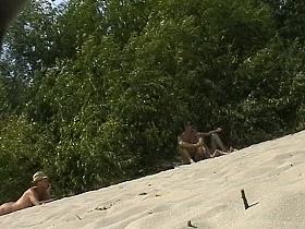 Spy camera on a nudist beach focuses on a sexy brunette