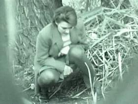 A business woman goes to take a piss in the autumn forest