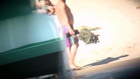 Topless ladies surrounded by dressed men at the beach