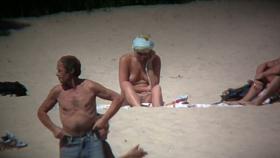 Horny naked brunette woman teasing her mates on the beach