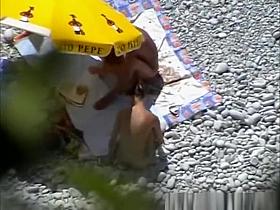 Nudists having sex under the sun umbrella