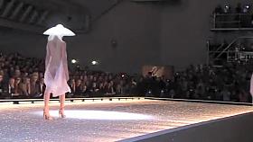 Seductive fashion model in a weird hat walks down the catwalk in the nude