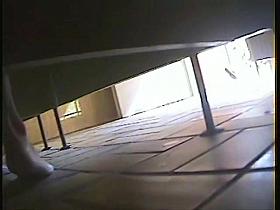 A bikini wearing girl is pissing in beach toilet