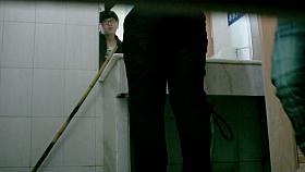 an Asian chick wearing glasses pissing in the public toilet