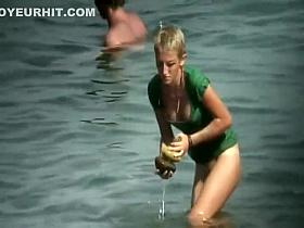 Nudist girl washes a towel in the water