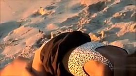 Attractive doll enjoys a man's cock in the sand