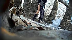 Ginger bridesmaid makes water behind a tree in the forest