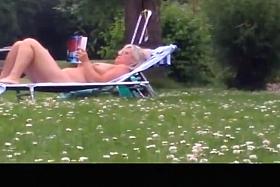 Nude mature woman reading a book