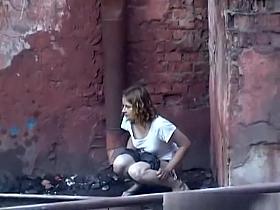 Girl pees in public next to old buildind