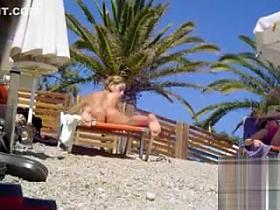 Tanned blonde takes off her bikini after a swim