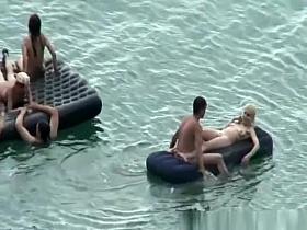 Group of nudist in air mattress in the water