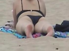 Candid beach babe is lying on the golden sand in bikini 03z