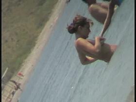 Nudist video at the beach has shy girl playing in the water