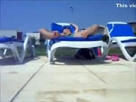 My wife in lounge chair stimulates her clitoris poolside