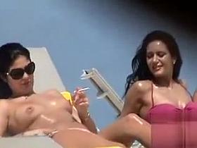 Oiled up topless hottie smokes a cigarette at the beach