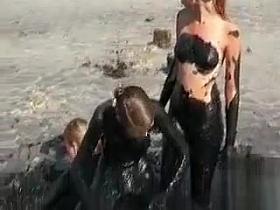 Young ladies coat their bodies in dark mud