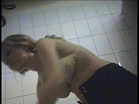 A milf is putting on a yellow striped bikini in the swimming pool changing room