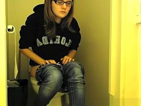 Girl in glasses pees in bathroom toilet