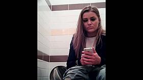 Amateur girl is playing with phone pissing on toilet