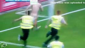 Streaking guy runs around the football pitch