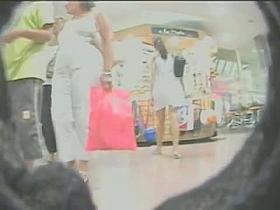 Upskirt video of a brunette in a white dress being pursued by a voyeur