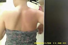 Topless blond girl is trying on new bra in the changing room